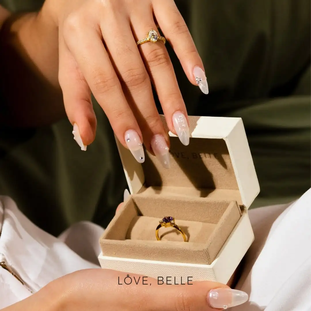 A hand opening a Love, Belle ring box